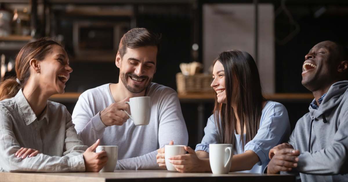 Personas riendo bebiendo café juntos 